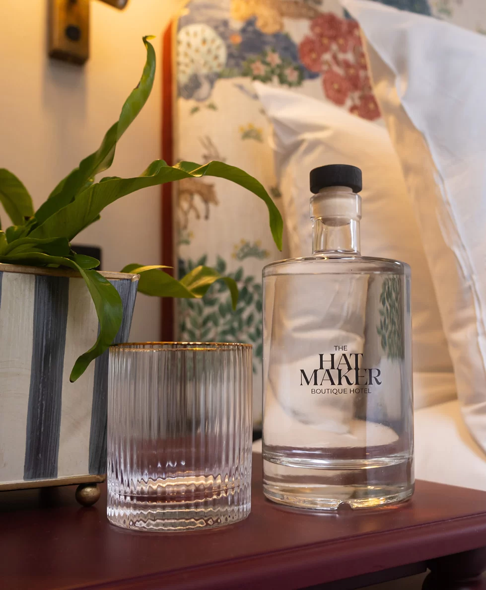 glass bottle of water on a nightstand with an empty gold rimmed glass