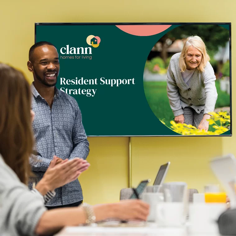 a young black man presenting a Powerpoint presentation on a large screen to people in front of him